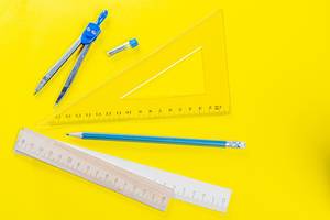 Drawing kit-ruler, compass and pencil on yellow background