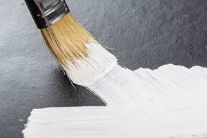 Draws a brush with white paint on a black background close-up