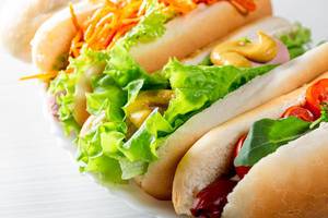 Drei frische, selbstgemachte Hotdogs, mit Sauce und Salat
