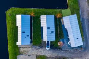 Drei Häuser am Wasser aus der Luft fotografiert in Akmarijp, Niederlande