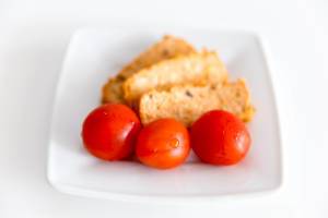 Drei reife Tomaten mit dem mediterranen und veganen Bio-Tofu Rosso von Taifun, auf einem weißen Teller