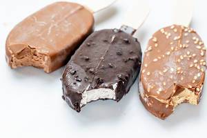 Drei verschiedene Schokoladeneis am Stiel auf weißer Oberfläche