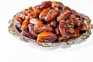 Dried dates in a vintage metal tray on white background