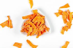 Dried pumpkin slices in a white bowl, top view