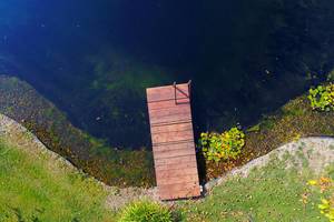 Drohneaufnahme eines Holzstegs an einem ruhigen See