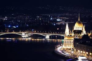 Drohnenbild des angestrahlten Parlamentsgebäudes in Budapest, Ungarn, bei Nacht