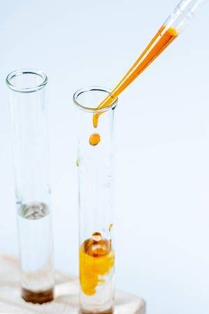Drops of orange liquid fall into a glass laboratory tube (Flip 2020)