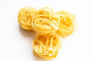 Dry tagliatelle pasta on white background  Flip 2019