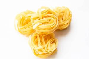 Dry tagliatelle pasta on white background.jpg