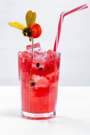 Durstlöschender Wassermelonen-Cocktail mit Trinkhalm und Dekoration vor weißem Hintergrund