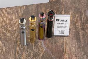 E-Zigaretten Uwell Whirl Kit 22 in silberfarben, goldfarben, regenbogenfarben und schwarz auf Holztisch