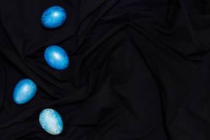 Easter concept. Easter festive eggs painted in trendy classic blue color on the dark textile.jpg