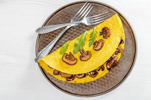 Egg omelet with mushrooms and arugula leaves and forks. Top view (Flip 2019)