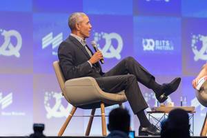 Ehemaligen US-Präsident Barack Obama sitzt im Talk der Startup-Konferenz in München auf einem Sessel auf der Bühne