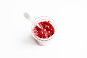 Ein Glas mit Erdbeer-Marmelade auf weißem Hintergrund - Aufsicht