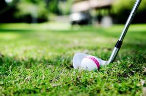 Ein Golfball mit einem Golfschläger auf dem Rasen