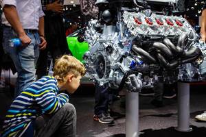 Ein Junge schaut in das Innere des Motors vom Audi R8 V10 plus
