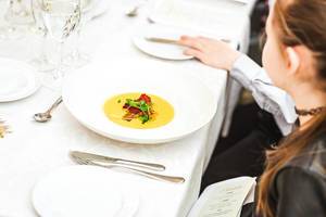 Ein Mädchen sitzt vor einem Teller Kürbissuppe mit getrocknetem Gemüse in einem Restaurant