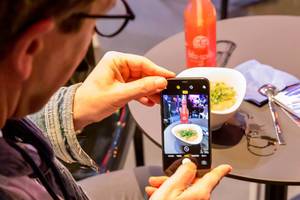 Ein Mann macht ein Bild von seinem Essen und seinem Getränk mit dem Smartphone