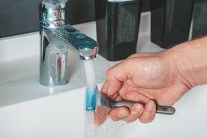 Ein Mann wäscht einen Handrasierer unter fließendem Wasser