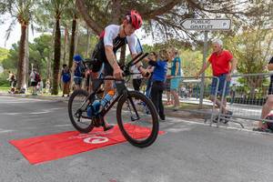 Ein Sportler mit einem roten Helm und der Nummer 112 steigt auf ein Rennrad beim Challenge Triathlon 218 in Peguera