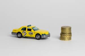 Ein Taxi mit einem Stapel Münzen auf weißem Hintergrund