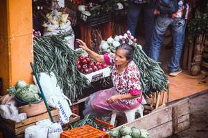 Eine Alte Dame verkauft Gemüse und Obst auf dem Markt