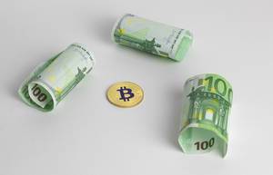 Eine Bitcoin-Münze mit Euroscheinen
