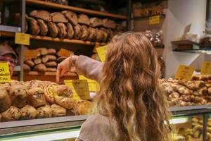 Eine Frau wählt ein Brot bei einem Bäcker auf dem Markt in Rom