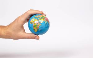 Eine hand hält einen Globus auf weißem Hintergrund
