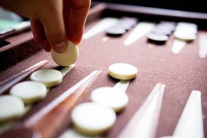 Eine Hand nimmt eine Backgammon Spielmünze
