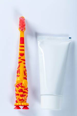 Eine Kinder-Zahnbürste mit einer Tube Zahnpasta auf weißem Hintergrund
