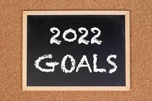Eine Kreidetafel zeigt den Text "2022 Ziele" auf englisch, mit einer Pinnwand aus Kork im Hintergrund
