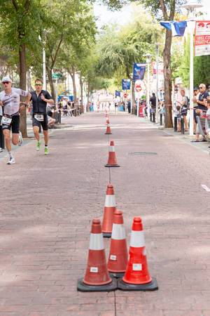 Eine Linie aus Aufstellhütchen teilt die Laufstrecke eines Triathlons. Die Triathleten Julian Hegg und Jesper Nybo Riis laufen um die Wette