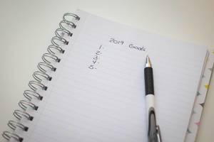 Eine Liste mit Zielen für das neue Jahr 2019 auf einem Notizbuch mit Kugelschreiber