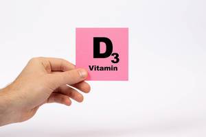 Eine Notiz mit der Aufschrift Vitamin D3 in der Hand gehalten auf weißem Hintergrund