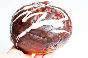 Eine Person hält einen Donut mit dunkler und weißer Schokolade vor weißem Hintergrund Nahaufnahme
