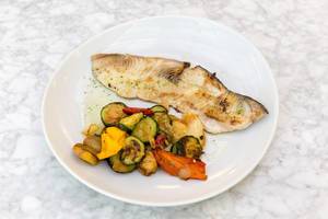 Eine Portion gegrillter Schwertfisch mit blanchiertem Gemüse auf einem weißen Teller
