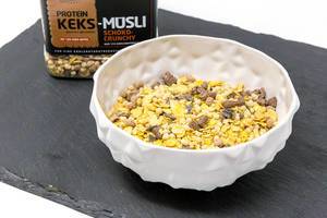 Eine Schale mit Layenberger Low Carb Protein Keks-Müsli in der Variation Schoko Crunchy mit Verpackung