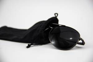 Eine schwarze Piloten-Sonnenbrille in einem Sonnenbrillen-Etui auf weißem Hintergrund