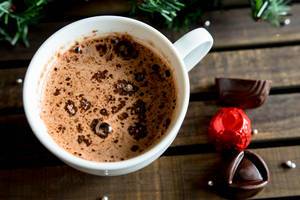 Eine Tasse heiße Schokolade mit Schokoladen-Bonbons und Tannenzweigen