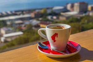 Eine Tasse Julius Meinl Kaffee einem Geländer - Bokeh