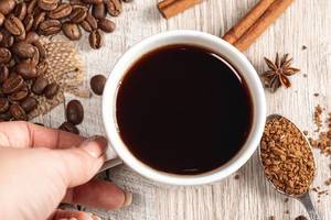 Eine Tasse Kaffee mit Zimt, Anis und Kaffeebohnen auf einem Holzhintergrund Top-view
