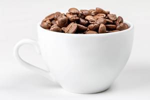 Eine weiße Tasse voll mit gerösteten Kaffeebohnen