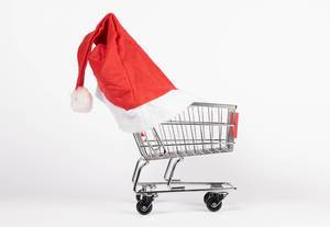 Einkaufswagen trägt Weihnachtsmütze und symbolisiert Weihnachtseinkäufe