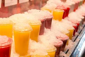 Eisgekühlte bunte Smoothie Saft-Getränke in Plastikbechern in der spanischen Markthalle Mercat de San Josep in Barcelona