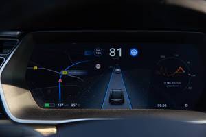 Electric Car Tesla Model S driving in autopilot - instrument panel / cluster shows street camera, navigation system and speed indicator