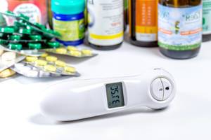 Electric thermometer, bottles and blisters with pills on white background (Flip 2019)
