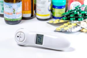Electric thermometer, bottles and blisters with pills on white background