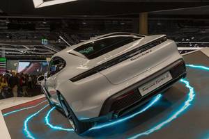 Elektroauto zur Showpräsentation auf beleuchteter Ausstellungsplattform: Taycan Turbo S E-Auto von Porsche